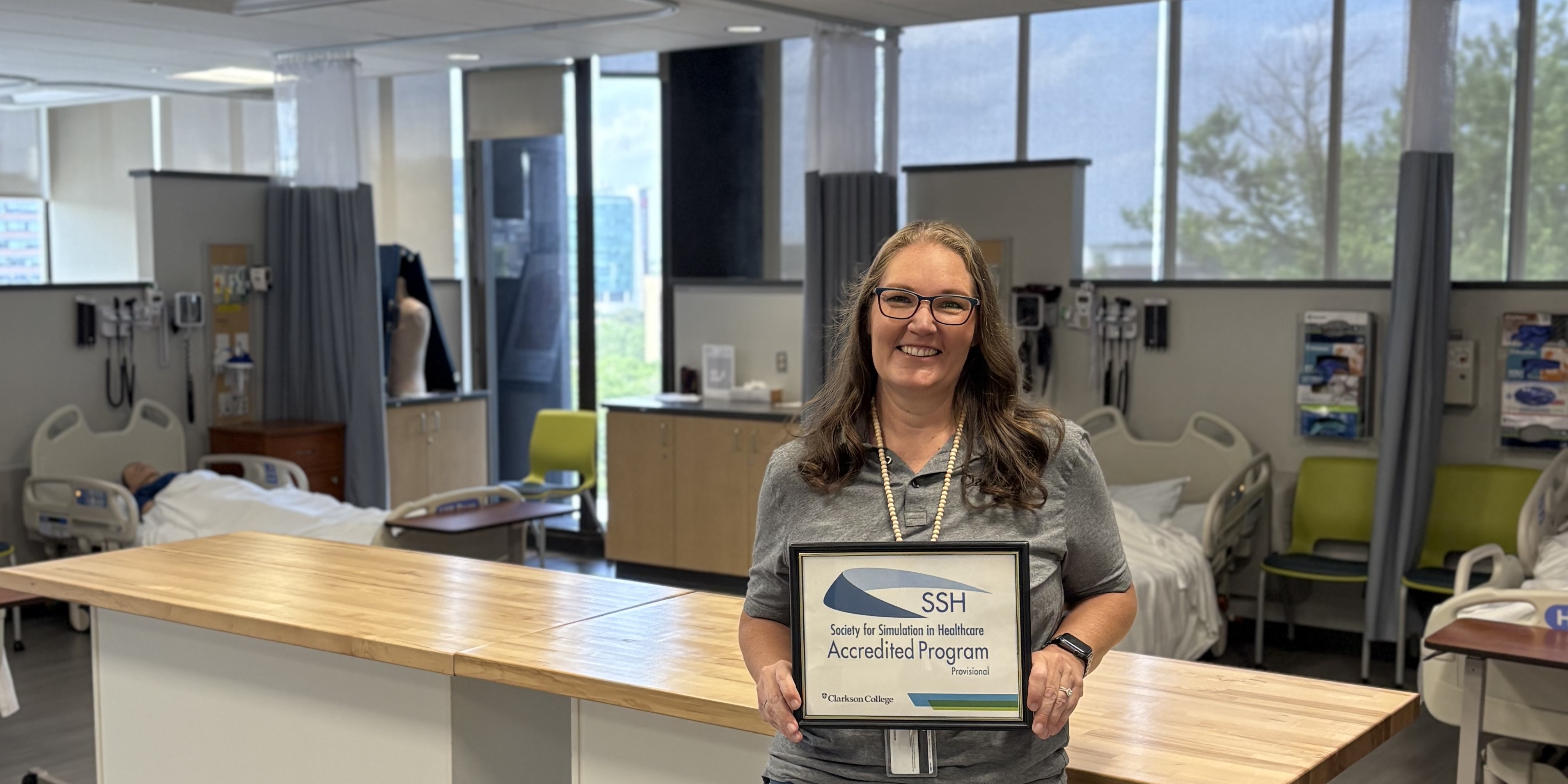 Sally Stimson holding a certificate of accreditation outside the ISC.